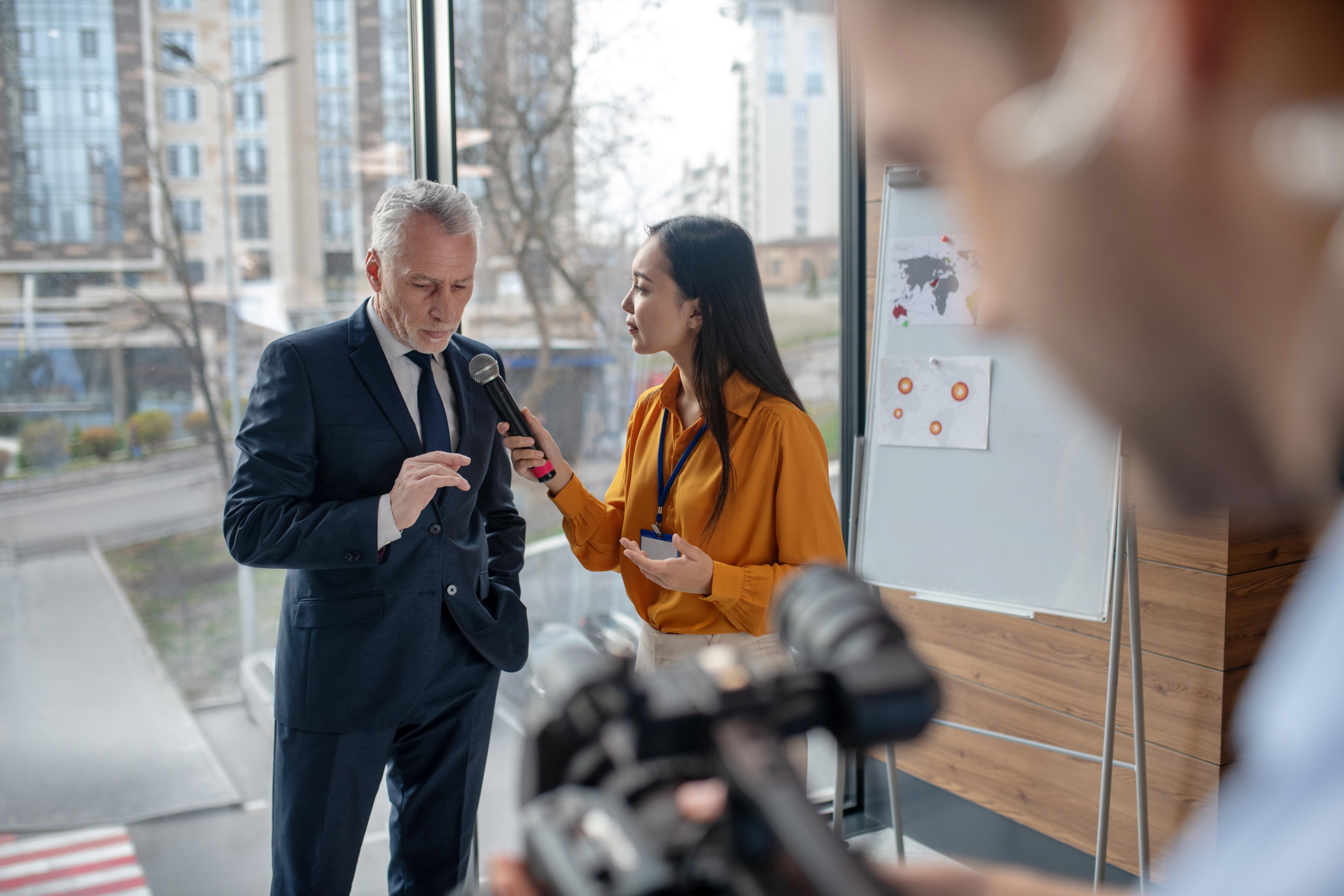 Young female reporter interviewing a man on the street