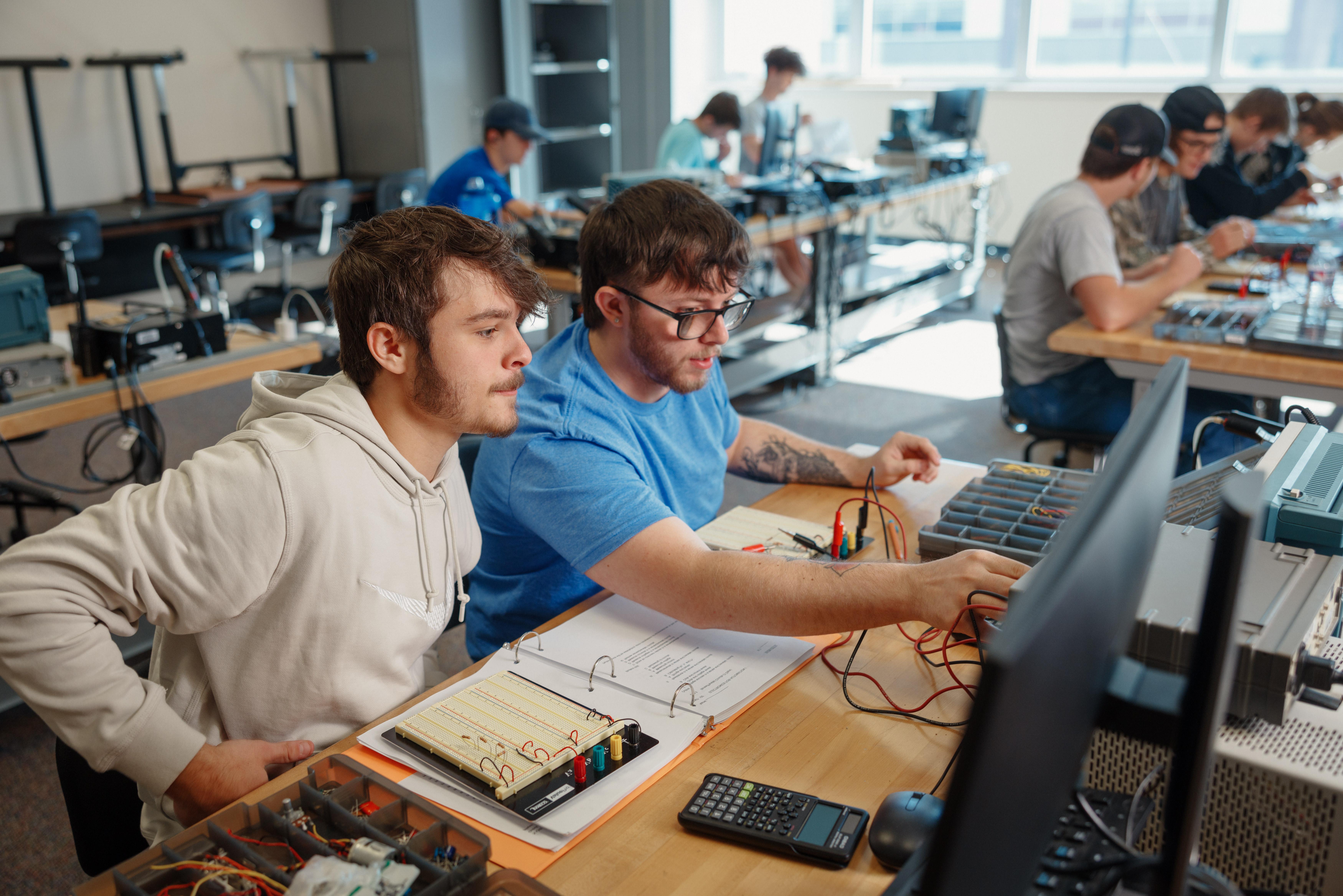 tech/manufacturing-technology-images/students-working-on-a-computer-with-some-machinery-under-them-overhead-camera-view